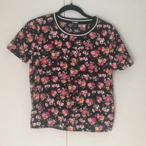  - Svart topp med blommönster i rosa och aprikos. Slits i ryggen som ger toppen karaktär. Använd ett fåtal gånger 