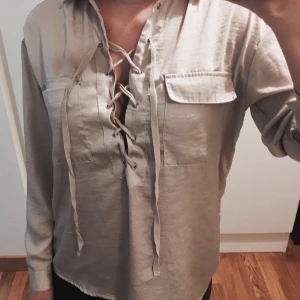  - Beige blus med snörning över bröstet, passar även 34 