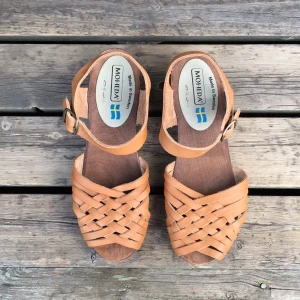  - Mohedatoffel med klack i brunt flätat skinn.
Klackhöjd: 6,5cm
Använda ett fåtal gånger.

🍃🌻🍃🌻🍃🌻🍃🌻🍃