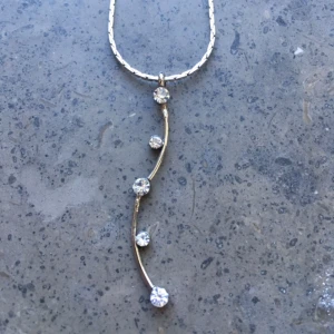  - Halsband i silver med små kristaller på hängande stav.  Frakt 7 kr.  Betalning via swish, kontoinbetalning eller via Plick.  Kolla gärna in mina andra annonser också. Jag säljer smycken, väskor, sjalar, kläder och skor. Kan samfrakta. 