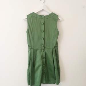 Kort klänning i ett blankt grönt tyg