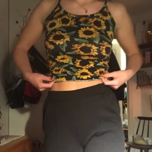 Linne med Solrosor - Min vackra topp med solrosor söker ett nytt hem! toppen är i ett mjukt bomullstyg och har en öppen rygg. Den sitter tajt och snyggt!🌻 Passar perfekt till ett par kostymbyxor eller enkla jeans. Möts helst upp, annars står köparen för frakt.