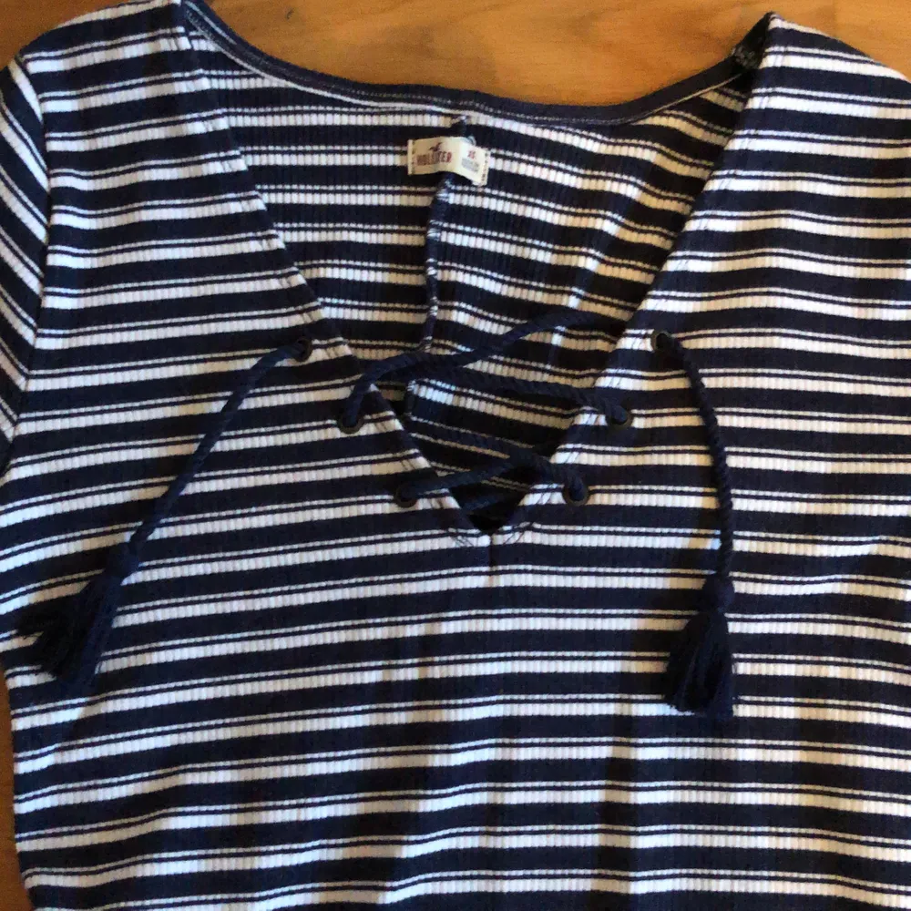 ribbstickad miniklänning i marinblått och vitt med snörning på bröstet och trekvartsärmar. Klänningar.