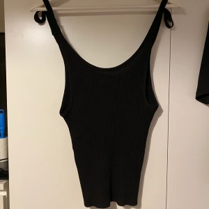 Svart ribbat linne - Svart ribbat linne med knytningar på axlar och djupare i ryggen