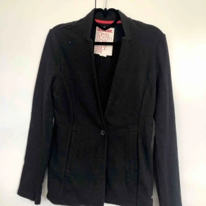  - En mörkgrå oanvänd tröja från MQ, i kavajmodell. Köparen betalar frakt