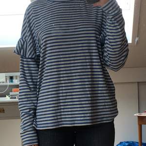En långärmad tröja från hm som är blå och vit randig. Har även en väldigt fin volang detalj på armarna. 