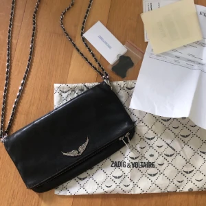 Zadig Voltaire väska svart - Jag säljer nu min svarta, trendiga zadig på grund av att jag inte använder den så mycket. Den är sparsamt använd med få slitage som man bara ser om man tittar noga. Väskan är köpt förra året på Boozt.com för 3300kr. Priset är förhandlingsbart!