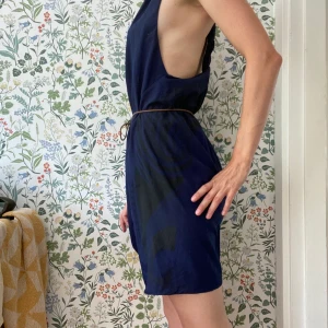 Acne klänning - Mörkblå klänning med svarta detaljer på ena sidan. Väcker i ryggen. Tunnt band i midjan medföljer. Använd ett fåtal ggr, bra skick. 