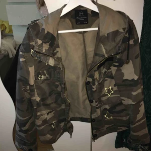  - En tunn jacka i kamoflach. Med stjärnor i guld och en luva.