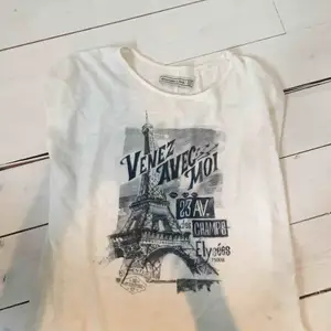 Vit, lite krämvit, t-shirt från Abercrombie med blått paris-tryck och lite paljetter-isch. Storlek XS, passar även S, använd men i superfint skick. Mjukt tyg, nypris ca 500 kr