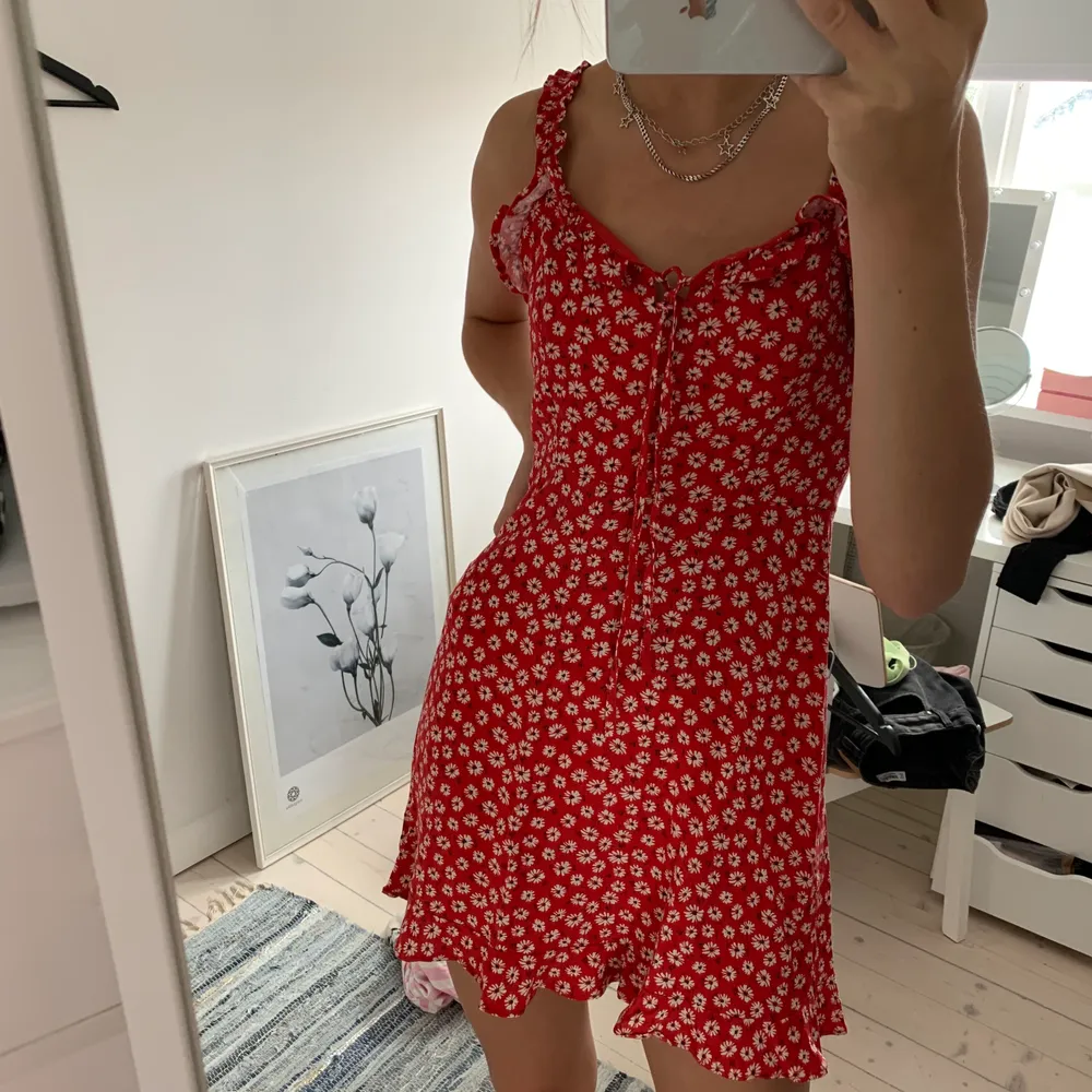 Säljer den perfekta klänningen, då den tyvärr är lite kort på mig (177cm) från pull&bear. I rött blommigt tyg och smockad i ryggen och med knytning framtill. Viker man ned den kan den  även bäras som en kjol:) . Klänningar.