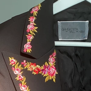 Kavaj - Croppad, svart kavaj med blommiga detaljer. Väldigt bra skick, säljer då den är stor på mig. Priset kan diskuteras.