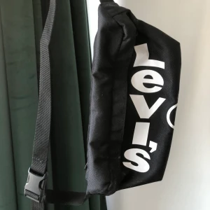 Midjeväska Levis - En svart magkänsla från Levis som använts kanske 3-4gånger bara! Bandet är väldigt justerbart så väskan passar alla🥰 Storleken är som normala storleken på denna sorts väskor, frakten ligger på ca 22-44kr