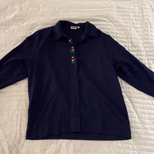 Mörkblå skjorta med broderade blommor - Mörkblå skjorta med broderade blommor. Från No1 i strl 36. Aldrig använd.