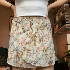 Supergullig kjol med blommönster - Lika snygg till bara ben på sommaren som kängor och stickad tröja på vintern! Snören fram (ja den sitter snett på ena bilden, snörena ska vara rakt fram 🙃). Ganska liten i storlek. Bra skick! Frakt tillkommer