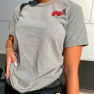 Comme des Garcons grå t-shirt  - grå t-shirt ifrån Comme des garcons med två hjärtan, nyskick! Storlek M (nypris ca 930kr) Buda i kommentarerna!