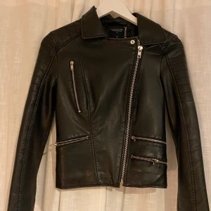 Skinnjacka  - Svart skinnjacka i oäkta skinn. Liknar den från chiquelle, bekväm och snygg! I bra skick bortsett från att kedjan man hänger upp jackan med har låsstnat på ena sidan. För liten för mig men har älskat denhär jackan. 