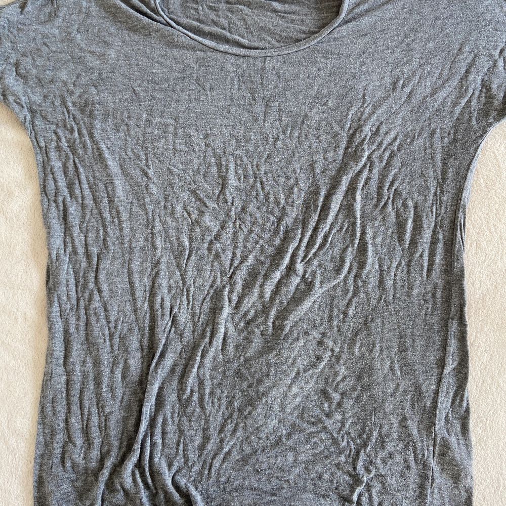 Grå t-shirt med svarta vingar där bak. Stor i storleken och väldigt pösig. Är gjord i 95% viskos och 5% elastan.. T-shirts.
