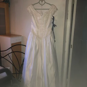 Brudklänning  - Vacker brudklänning med lång kjol i bak & rosett. Med pärlor på livet.