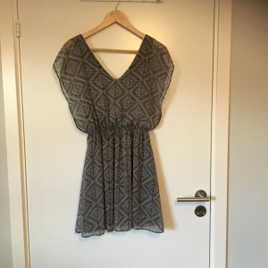 Mönstrad klänning från Vintage Love - Mönstrad klänning i svart och vit med guldfärgade detaljer från Vintage Love. Stl XS eller möjligtvis S, lapp saknas. Gott skick, knappt använd. Frakt betalas av köparen.