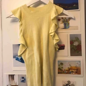  - Ett gult ribbat linne med volanger. Bra skick. 30kr