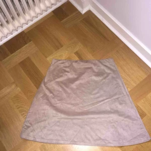  - Mjuk beige kjol i sammetstyg från Nelly. Oanvänd. Köparen betalar frakten