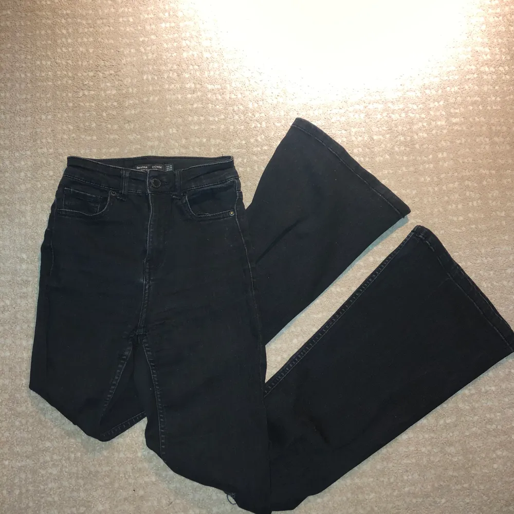 Svarta bootcut jeans från Bershka med hål på båda knäna. Jeanstyget är stretchigt och formar sig fint efter kroppen. Byxorna är använda, men fortfarande i fint skick.. Jeans & Byxor.