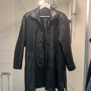 Läderkappa - Kappa i äkta läder. Sitter som en M eller stor S, delar sig med knappen på sidorna av kappan. 