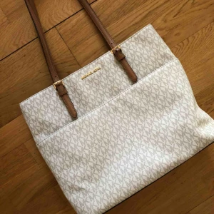  - Michael Kors väska i vit och brun färg. Fyra ytter- och innerfickor. Använt få gånger, perfekt skick. Säljes pga för lite användning. Ordinarie pris: 1 900kr 
