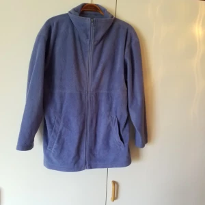  - Lilablå fleecetröja/jacka med fickor, står ingen storlek i men passar M, mimdre och större beroende på hur man vill ha den