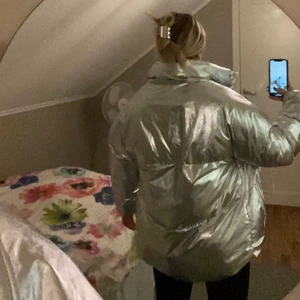Pufferjacket  - Silvrig super varm pufferjacket, medföljer luva med fusk päls som är lätt avtagbar. Jackan är fodrad intill med supersjuk material (bild går att få!!). Jackan kan även justeras till att bli mer bomber aktig och croppad med hjälp av dragsko nertill. 