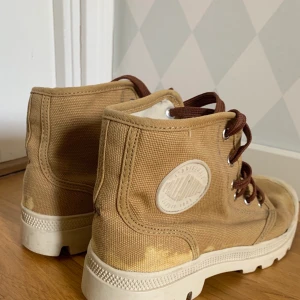 Skor från Palladium storlek 37 - Ljusbruna skor med mörkbrun snörning i storlek 37. Lite förgavfall på baksidan av skons tyg. 