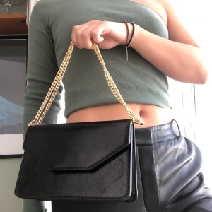 Helt ny Mango väska - Precis köpt denna väldigt snygga svarta väska med guldiga axelband från Mango, kom dock på att jag redan har en liknande så vill gärna sälja vidare! Aldrig använd och lappen kvar. Det går att ha axelbanden på väldigt många olika sätt oxå! BUDA