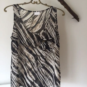  - Oanvänd top/blus från vila i stl M. Snygg detalj med ficka på ena bröstet.   Garderobsrensning, se mina övriga annonser. Möjlighet till samfrakt.   Köparen står för frakt. Ansvarar ej för postens ev slarv.