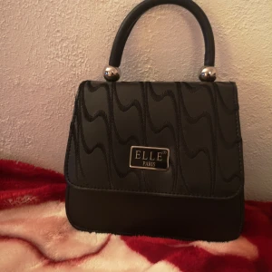 Elle - Fin söt Elle-inspirerad handväska i nyskick, använd endast en gång. Storlek ca 20x20 cm. 3+1 fack inuti. Pris 100 kr + ev frakt. Finns i Sthlm/Uppsala