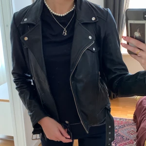 Skinnjacka - Kort skinnjacka i äkta skinn. Strl 34. Använd och har en del slitningar vid armarna och på slagen. 