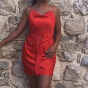 Röd/orange silk klänning  - Säljer min skit snygga klänning för 200 och jag köpte den 2019 för ungefär 400kr från river island. Har använt den två gånger och är i perfekt skick. Säljer den då jag använder den så sällan. Knuten i midjan ’stylar’ du den själv. Klänningens material är silk om inte jag är ute och cyklar. Klänningen har även justerande band! Har ni några frågor kan ni kontakta mig❤️ frakt ingår ej!