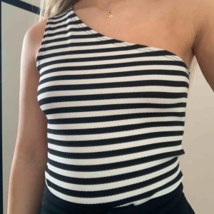  - Svart-vit-randig one shoulder body ursprungligen från Gina Tricot. Går att knäppa i grenen. Passar någon med mindre byst. Sparsamt använd, bra skick. 