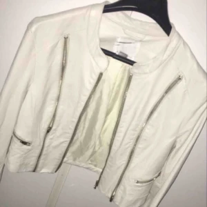  - En vit och kort skinnjacka med kedjor på sidorna den är använd par gånger men ändå jätte skön att ha köpte den 250kr Köparen står för frakt.