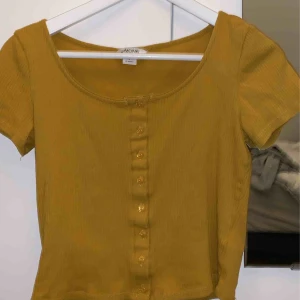  - Senapsgul top med knappar från Monki 