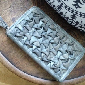  - Större clutch/plånbok i grått genuint skinn med flätad framsida och två dragkedjor och flera fack inuti. Ett fack med dragkedja på baksidan. Från danska By Burin. Nypris 1299:-