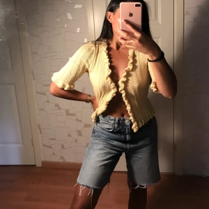 ASOS Stickad topp med volanger 36/S - Söt stickad topp med volanger från ASOS. Hel & ren i mycket fint skick. Ljusgul/beige. Volanger framtill & vid ärmslut. Storlek 36/S. 