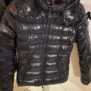 Moncler Bady  - Moncler jacka i modellen Bady.Jackan är väl använd men inga defekter. Jackan är normal i storlek, 00 motsvarar XXS men en liten XS kan också ha den. Avtagbar huva. Köpt på NK hösten 2016 och kvitto har kommit bort vid flytt. Nypris var strax under 10.000 