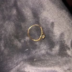 Guldring  - Säljer lite ringar som jag gjort själv, ringen är gjord av guldig ståltråd och en svart pärla/Sten med små blommor på. Säljer denna ring för 15 kr+ 11 kr i frakt. DMa mig vid intresse!