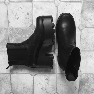 Svarta klumpiga boots i nyskick st 39 - Ett par supersnygga klumpiga skor med klack i 70-tals stil. Enkla att dra på sig. St. 39. Använda några två-tre gånger bara, därav i nyskick! Mått: 22 cm och klacken är 8 cm som högst. Från märket "Tata Italia".   Hör av dig om du har någon fundering!