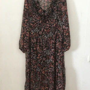Blommig klänning - En sval, skön blommig klänning med fastsydd svart underklänning. Knappt avnänd. Small men stor i storleken. 