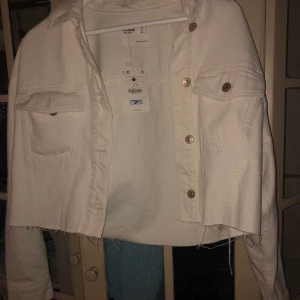 Jeans jacka - Vit croppad jeans jacka från Bershka. Jackan är helt oanvänd och därför i väldigt bra skick! Skickar mot att köparen betalar frakt!💜 Kan även mötas upp i Uppsala, eventuellt Sthlm:)