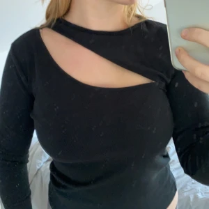 Svart skuren tröja - Svart tröja med skurning ovanför bröstet. Ribbad i tyget och skön och stretchig.