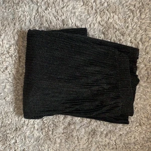 Byxor från NAKD - Ett par svarta glittriga byxor från NAKD. Se bild 2 för hur de sitter på mig som är 180cm lång. Normal storlek och stretchiga i midjan. Säg till för fler bilder!