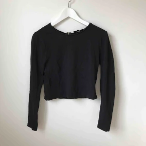  - Svart långärmad, kort topp med silverdragkedja i ryggen.  Köparen står för fraktkostnad enligt postens portotabell.